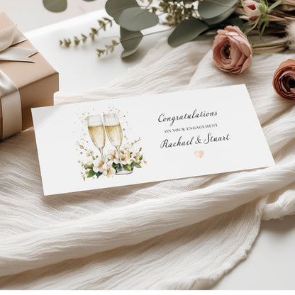 Engagement card money wallet with a champagne glasses and flowers design, on a soft fabric background