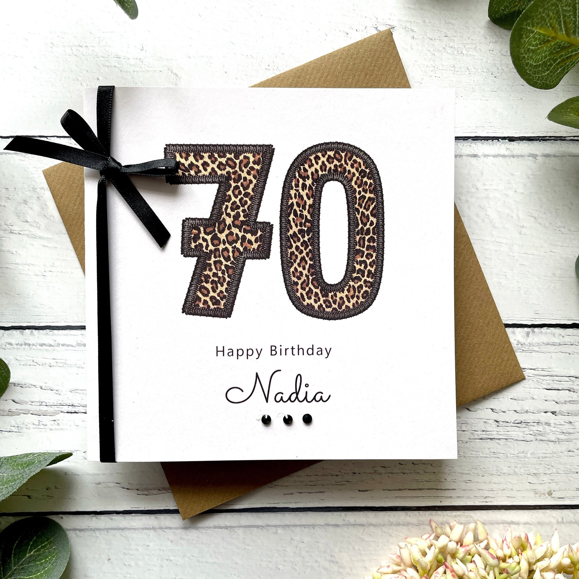 Birthday card with leopard print numbers '70' and a black bow on a white background