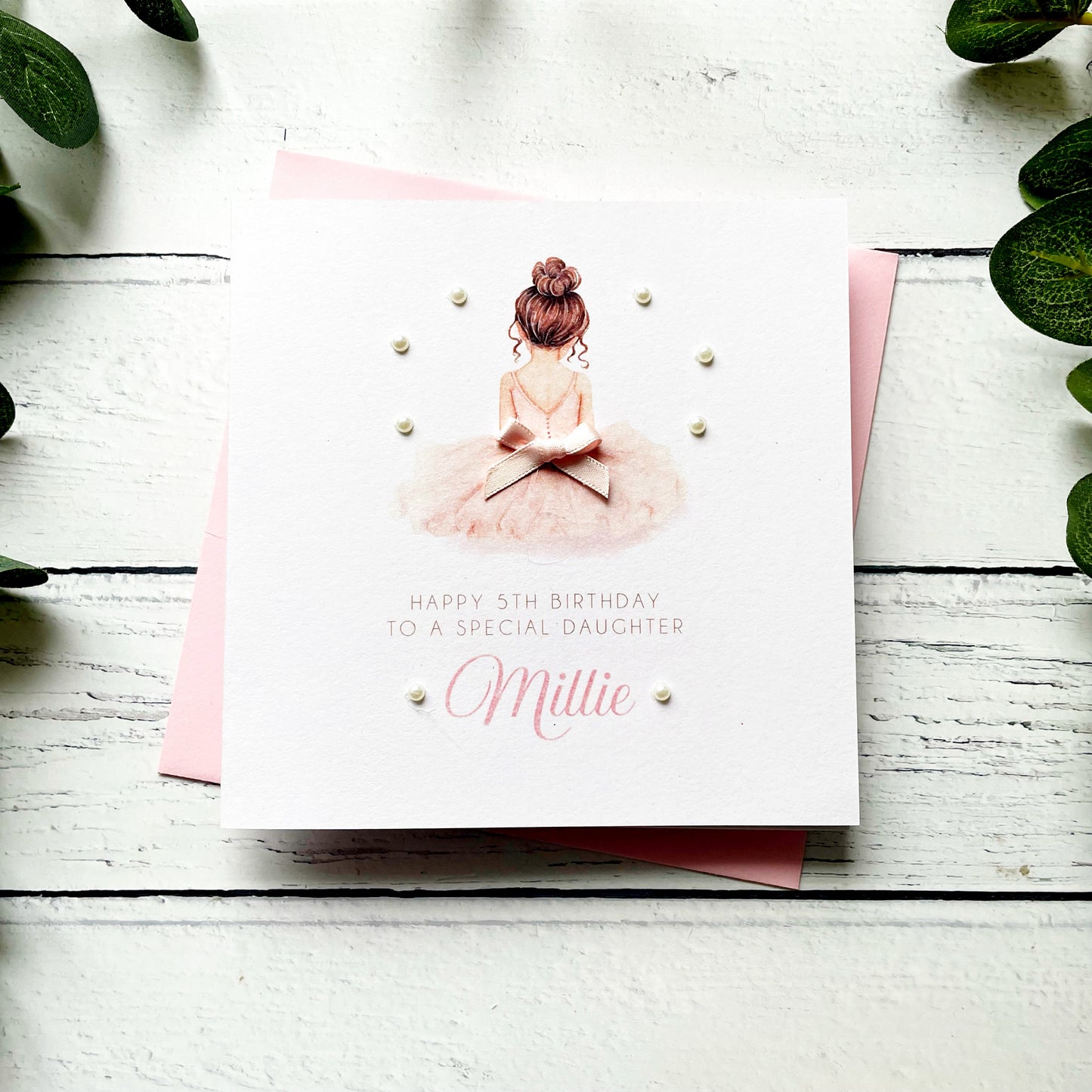 Birthday card for a special daughter with a ballerina illustration on a white wooden surface.