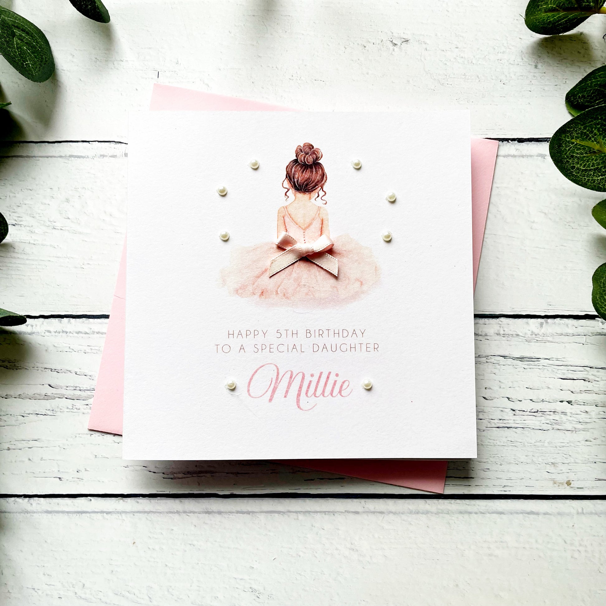Birthday card for a special daughter with a ballerina illustration on a white wooden surface.