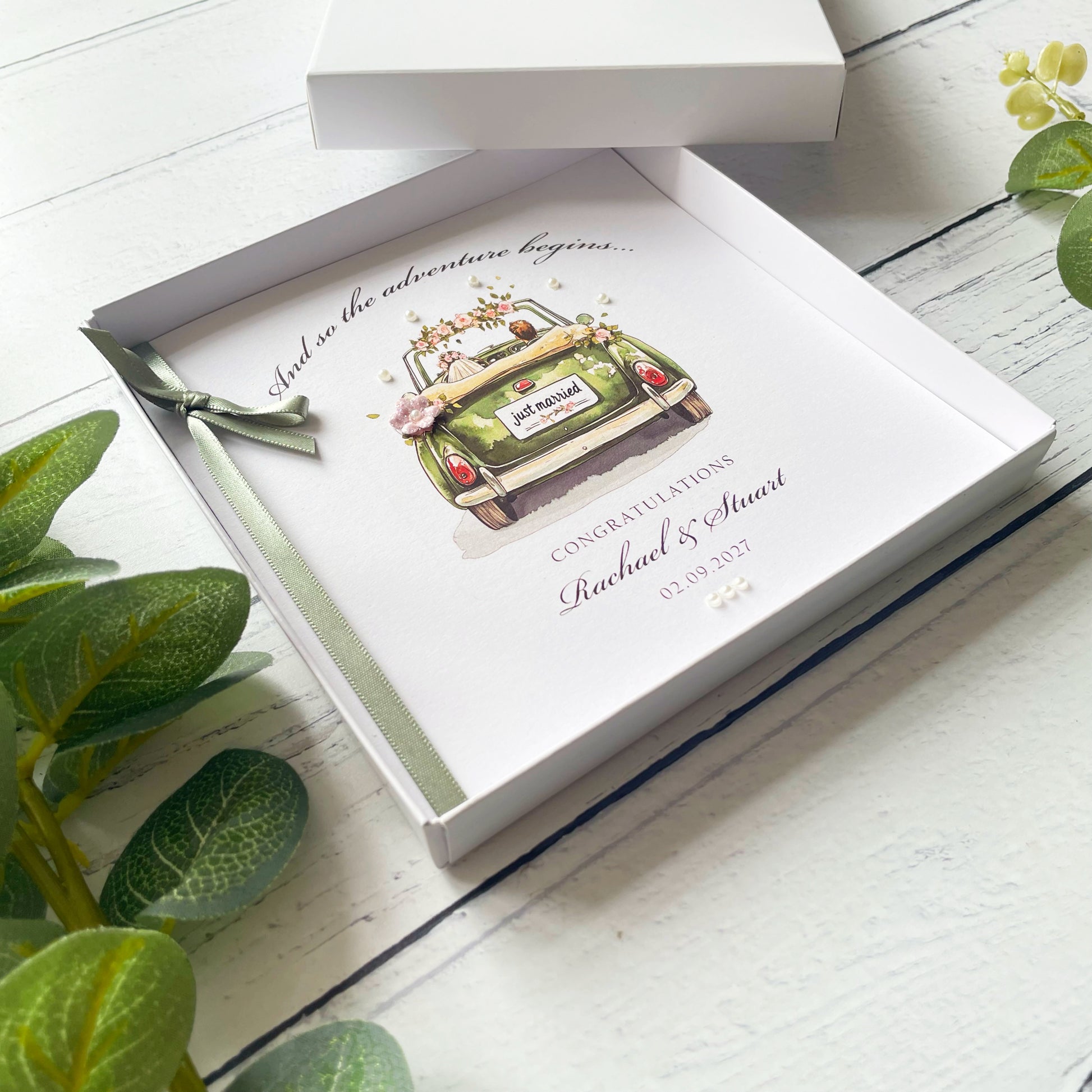Wedding card with a car illustration and personalised text on a white surface 