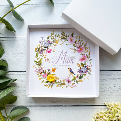 Greeting card with floral design and text 'To a wonderful Mum on your birthday' in a white box on a wooden surface.