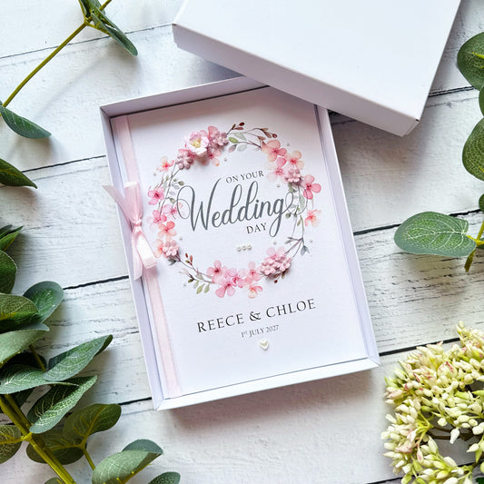 Wedding card with floral design and text 'On Your Wedding Day'  and personalised text in a decorative box on a white wooden surface.