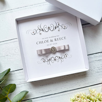 Personalised wedding card in a box. With a pleated bow and crystal embellishment. With text on your wedding day, followed by names and wedding date.