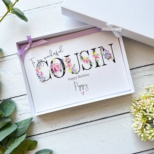 Greeting card with floral text 'To my wonderful Cousin' on a white wooden surface with greenery.