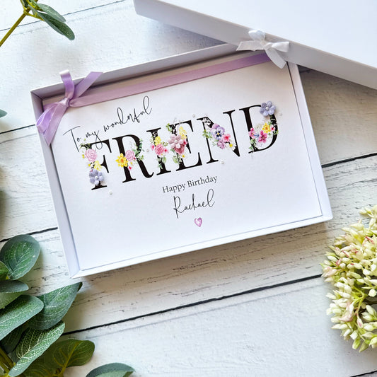 Greeting card with 'To my wonderful friend' text and floral decorations, tied with a ribbon on a wooden surface.