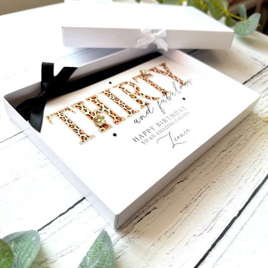 Greeting card in a box featuring the text Thirty and Fabulous in a leopard print design. Finished with a black bow, gold paper flowers and black gems.