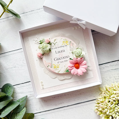 Personalised floral card in a decorative box on a wooden surface with plants around.