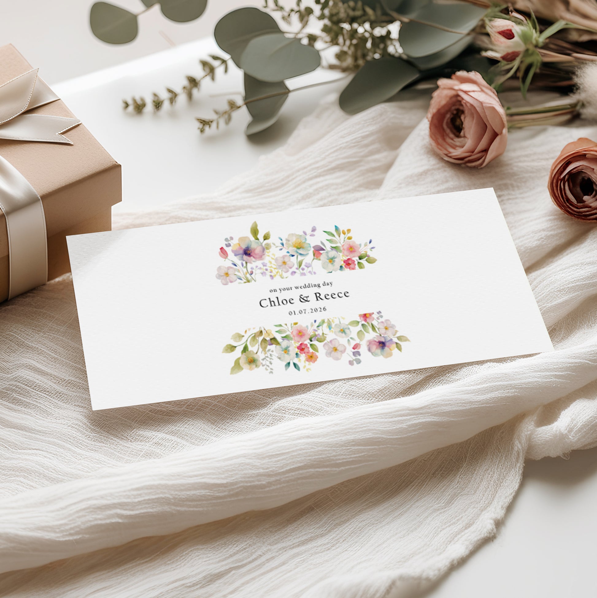 Floral money wallet card with personalised names and wedding date on a soft fabric background 