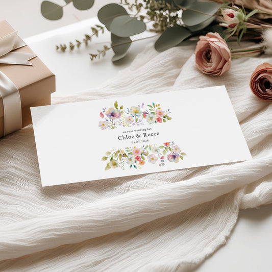 Floral money wallet card with personalised names and wedding date on a soft fabric background 