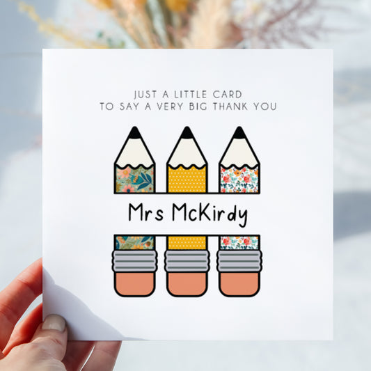 Personalised thank you teacher greeting card featuring three patterned pencil illustrations and the custom teacher name “Mrs McKirdy” across the centre. The card reads “Just a little card to say a very big thank you.” Displayed being held in hand against a softly blurred neutral background.