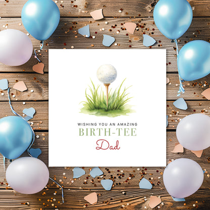 Greeting card with golf ball and tee design, surrounded by balloons and confetti on a wooden background.